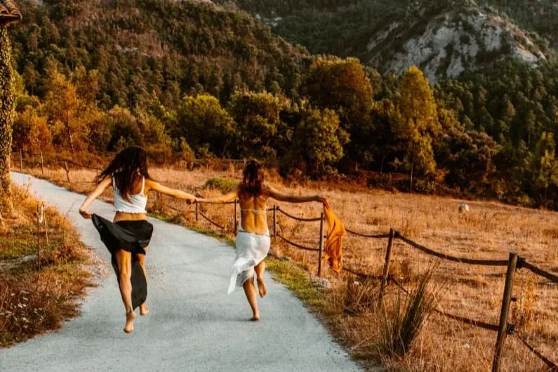 Dos mujeres corriendo por un camino de montaña, de espaldas